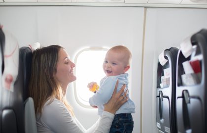Young mom, playing and breastfeeding her toddler boy on board of aircraft