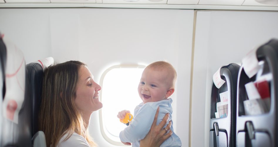 Young mom, playing and breastfeeding her toddler boy on board of aircraft